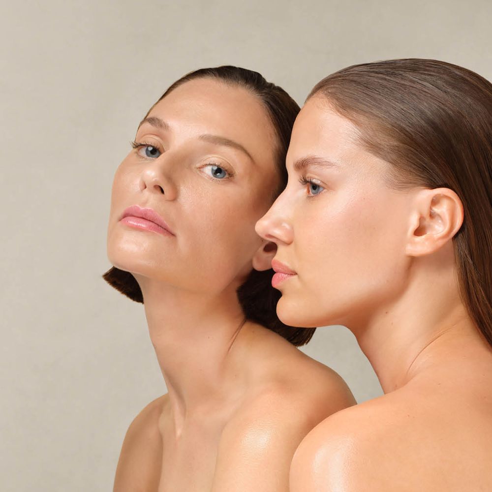 Zwei Frauen mit glatter Haut und zurückgekämmtem Haar, eine blickt frontal, die andere im Profil